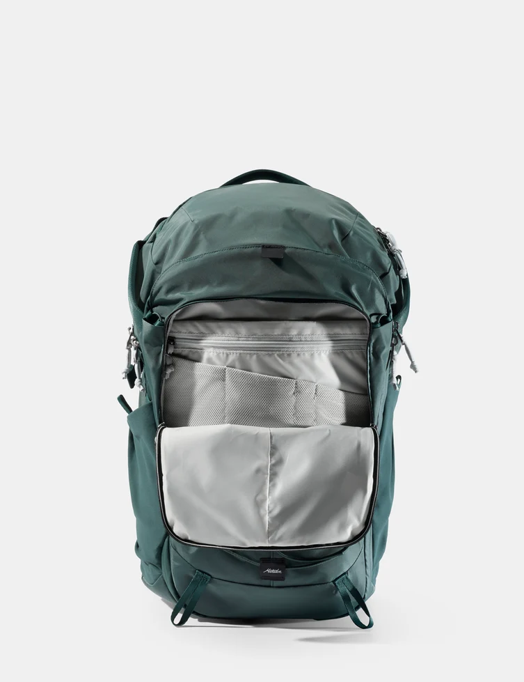 杜松綠款 Adventure Pack 24L 正面，前袋拉開露出淺灰色內部隔層