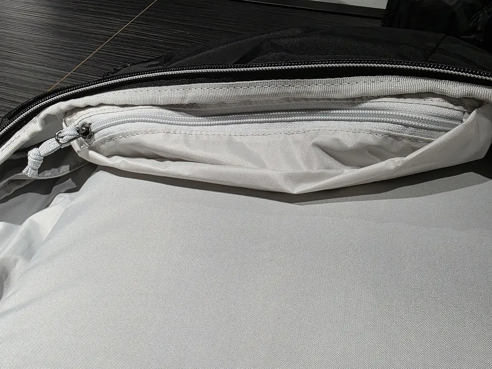 從頂部開口看進主艙，開口內側有一個白色拉鍊袋，拉鍊頭帶繩結拉片
